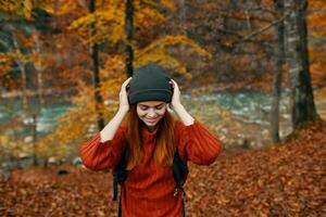 contento donna escursionista nel il autunno foresta vicino il fiume Esprimere a gesti con sua mani copia spazio foto