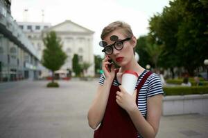 bella donna con bicchieri parlando su il Telefono su il strada stile di vita foto