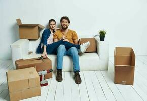 sposato coppia nel il appartamento su il divano con scatole in movimento divertimento foto