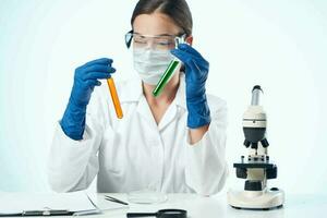 femmina laboratorio assistente indossare giallo bicchieri chimico soluzione microscopio ricerca biotecnologia foto
