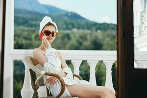 alla moda donna seduta su il balcone parlando su il Telefono Perfetto soleggiato mattina foto