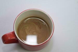 vicino su caldo cappuccino caffè nel un' rosso tazza isolato su un' bianca sfondo foto