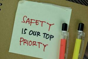 sicurezza è nostro superiore priorità Scrivi su appiccicoso Appunti isolato su di legno tavolo. foto