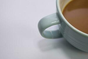 vicino su caldo cappuccino caffè nel un' blu tazza isolato su un' bianca sfondo foto