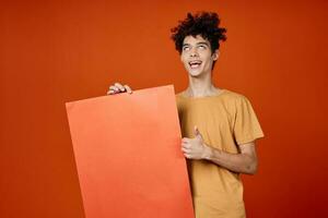 uomo con Riccio capelli Tenere un' manifesto nel mani copia spazio ritagliata Visualizza foto