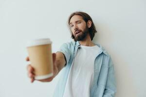 libero professionista del Millennio uomo con un' barba potabile caffè a partire dal un' riciclato tazza nel elegante fricchettone Abiti bianca maglietta blu jeans e camicia su un' bianca sfondo foto