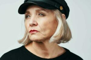 anziano donna nel un' nero cappello moda avvicinamento leggero sfondo foto