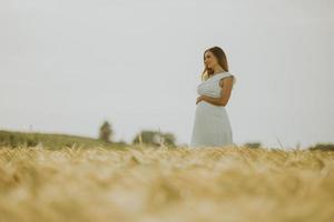 donna incinta in abito bianco in un campo di grano foto