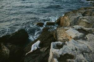 bellissimo giovane donna dire bugie su roccioso costa con crepe su roccioso superficie inalterato foto