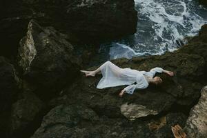 a piedi nudi donna dire bugie su roccioso costa con crepe su roccioso superficie paesaggio foto