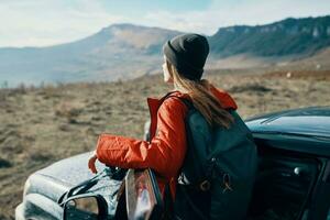 donna viaggi nel natura con un' zaino e vicino il auto foto