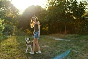 donna e sua rauco cane a piedi felicemente su il erba nel il parco Sorridi con denti nel il autunno camminare con sua animale domestico, viaggio con un' cane amico foto