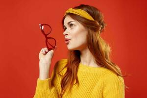 attraente donna con giallo bendare bicchieri nel il mani di studio Accessori foto