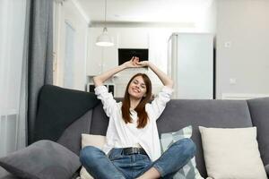 allegro donna seduta su il divano comfort riposo appartamento interno foto