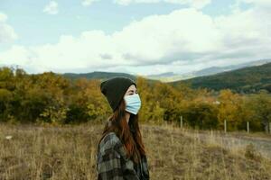 ritratto di un' donna nel un' medico maschera su un' prato nel il montagne autunno asciutto erba foto