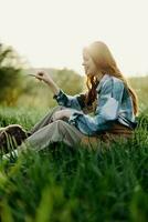 contento donna seduta nel natura e giocando con sua animale domestico nel il parco seduta su il verde erba nel il estate luce del sole nel il sera, giocando nel natura foto