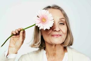 anziano donna nel bianca accappatoio fiore cura vacanza foto