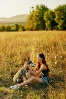 donna seduta nel campo con bassotto cane sorridente mentre la spesa tempo nel natura con amico cane nel autunno a tramonto mentre in viaggio foto