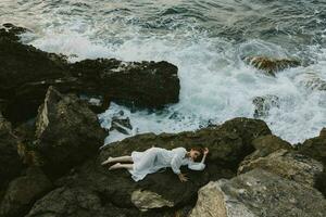 bellissimo donna dire bugie su roccioso costa con crepe su roccioso superficie natura paesaggio foto