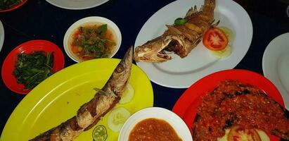 frutti di mare piatto servito su il tavolo e piatto a partire dal sopra con diverso genere di piatto a partire dal fritte pesce Barracuda, dentice, tonno mascelle, e anche mescolare di tropicale verdure foto