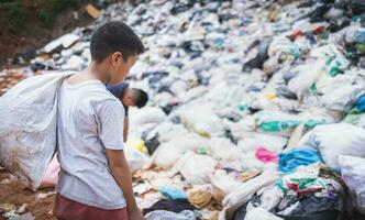 povero ragazzo raccolta spazzatura nel il suo sacco per guadagnare il suo mezzi di sussistenza, il concetto di povero bambini e povertà foto