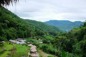 paesaggio valle montagna con collina tribù villaggio su verde collina e foresta nel piovoso stagione a Tailandia. foto