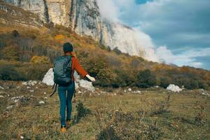 viaggiatore con zaino riposo nel il montagne all'aperto nel autunno paesaggio blu cielo rocce foto