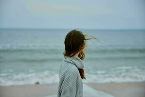 donna rosso capelli nel un' maglione di il oceano inalterato foto