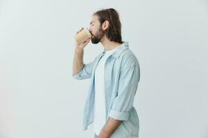 libero professionista del Millennio uomo con barba potabile caffè a partire dal un' Granchio tazza nel elegante fricchettone Abiti su un' bianca sfondo foto