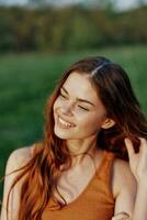 un' bellissimo dai capelli rossi donna ride e sorrisi con sua denti nel il luminosa tramonto luce del sole. il concetto di salutare vivente e bene nutrizione foto