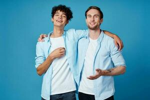 uomo con Riccio capelli abbracci il suo amico su blu sfondo divertimento ritagliata Visualizza foto