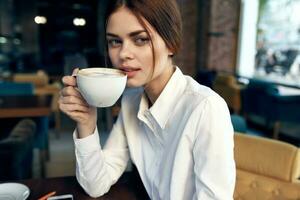 ritratto di un' bellissimo donna con un' tazza nel mano nel un' ristorante e interno nel il sfondo foto