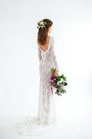 gioiosa sposa ragazza in un abito bianco lavorato a maglia in posa con un mazzo di fiori foto