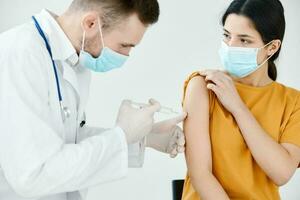 medico assistente iniezioni nel il spalla di un' donna indossare un' medico maschera covid vaccinazione foto