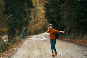 contento viaggiatore con zaino passeggiate su il strada nel autunno foresta foto