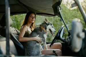 donna e rauco cane felicemente in viaggio nel auto Sorridi con denti autunno camminare con animale domestico, viaggio con cane amico abbracci e balli foto