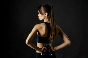 sportivo donna nel nero superiore con manubri nel mani ritagliata Visualizza di allenarsi esercizio foto