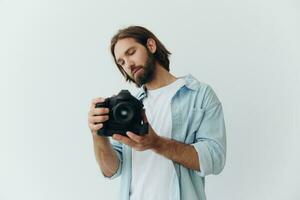 un' maschio fricchettone fotografo nel un' studio contro un' bianca sfondo sembra attraverso il telecamera mirino e spara scatti con naturale leggero a partire dal il finestra. stile di vita opera come un' libero professionista fotografo foto