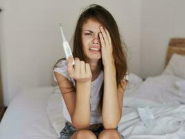 irritato donna pianto con un' termometro nel sua mani alto temperatura foto