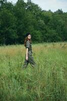 donna nel il prato natura passeggiate attraverso il campo contro il sfondo di alberi foto