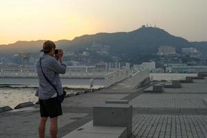 indietro ritratto di uomo asiatico in piedi e scattare la foto del paesaggio e del paesaggio urbano