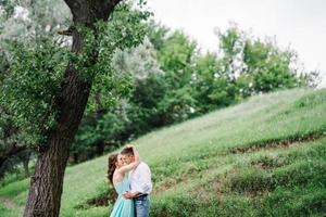 ragazzo felice in una camicia bianca e una ragazza in un vestito turchese stanno camminando nel parco della foresta foto