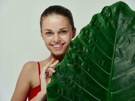 contento donna nel rosso costume da bagno con verde foglia catturare pulito pelle foto