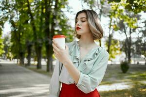 allegro donna con un' tazza di caffè nel il parco giù il strada tempo libero stile di vita foto