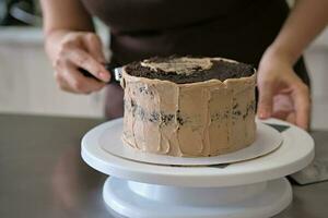 donna Pasticcino capocuoco fabbricazione cioccolato torta con cioccolato crema, avvicinamento. torta fabbricazione processi, selettivo messa a fuoco foto