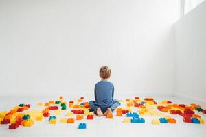mondo autismo consapevolezza giorno. senza volto bambino seduta solo nel bianca camera tra colorato enigmi. generativo ai illustrazione foto