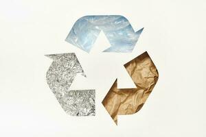 riciclare simbolo fatto di tagliare carta con plastica, carta e Foglio su blu sfondo. riutilizzare, ridurre, riciclare concetto foto