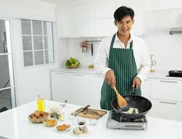 chef maschio asiatico che cucina riso fritto in cucina foto