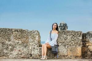 bellissimo donna su bianca vestito seduta solo a il muri circostante il coloniale città di cartagena de indie foto