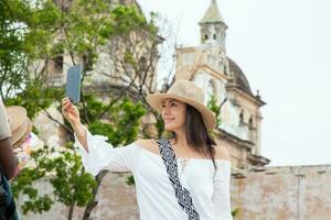 bellissimo giovane donna provando su cappelli per acquistare uno a partire dal un strada venditore nel cartagena de indie murato città foto